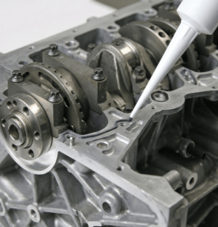 Image showing application of silicone sealant to an engine block during a high-performance engine rebuild